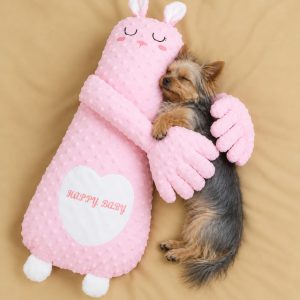 Yorkie sleeping in the arms of the pink bunny patting pillow